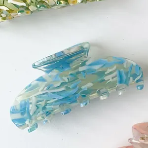 Detailed close-up of large blue and white acetate hair claw clip with stone textures