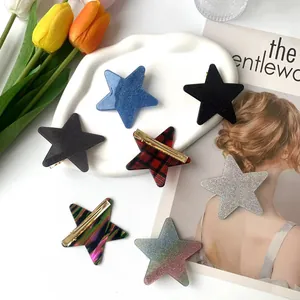 Star-shaped glitter and checkered hair clips displayed on a tray with flowers