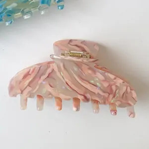 Macro detail of pink marble acetate hair claw clip with shimmering pearlescent finish