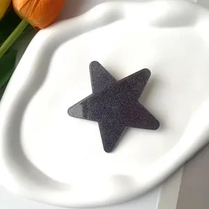 Detailed view of a glittering purple star-shaped hair clip on a white ceramic tray