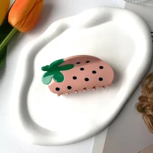 Haarklammer in Erdbeerform in Rosa mit grünen Blättern auf einem Dekotablett