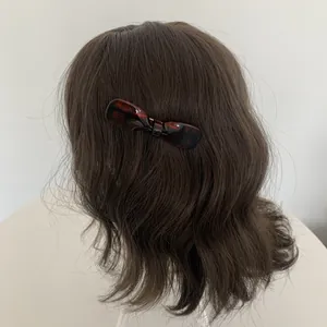 Detail einer dunkelbraun karierten Haarschleife auf gewelltem Haar mit Glanz und Textur