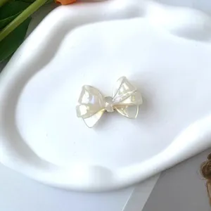 Detalle de una pinza de pelo con lazo crema irisado de acetato en una bandeja cerámica