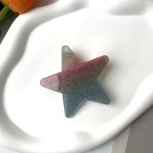 Macro detail of a glittery gradient star hair clip on a white ceramic tray with tulips