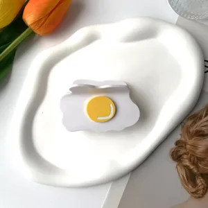 Haarklammer im Setzei-Design aus Acetat auf weißem Keramikteiler mit Blumendeko