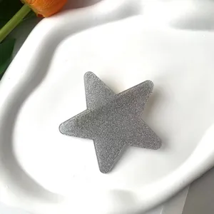 Macro shot of silver glittery star hair clip on a white decorative tray with tulip