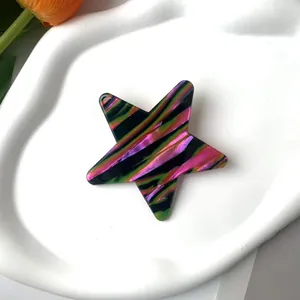 Macro shot of a colorful star hair clip with acetate stripes on a white wave tray