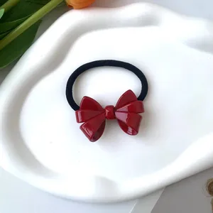 Detalle de una goma de pelo con lazo rojo brillante sobre una bandeja blanca