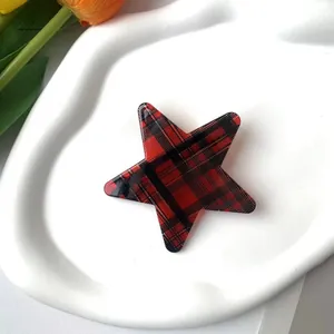 Detail of star-shaped red and black tartan hair clip on a white decorative ceramic tray