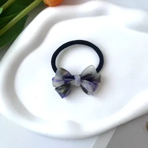 Detalle de un coletero con lazo y patrón de mármol morado en una bandeja con tulipanes
