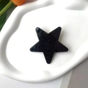 Macro shot of glittery black star pattern accessory on a white textured ceramic dish