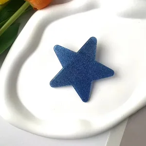 Macro detail of blue glitter star hair clip on a white ceramic tray with tulips