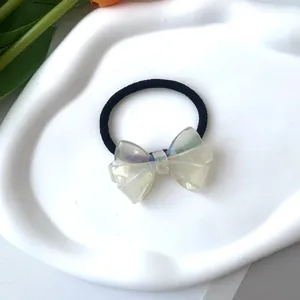 Detalle de una goma de pelo con lazo de acetato iridiscente y banda negra de alta elasticidad