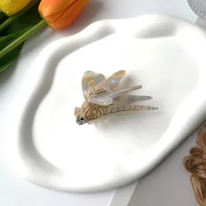 Détail d'une pince à cheveux en forme de libellule avec texture marbrée en acétate et or
