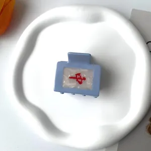 Light blue acetate square hair claw with red Mahjong Zhong character on white tray