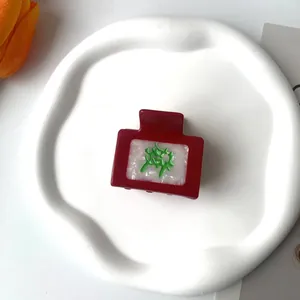 Cartoon acetate hair claw clip with mahjong character design on a white ceramic tray