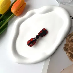 Detail of red and black checkered bow hair clip on a white decorative jewelry plate