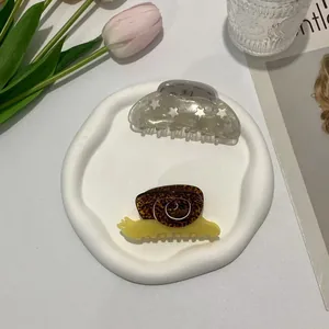 Detail of creative snail and star pattern acetate hair claws in a decorative setting