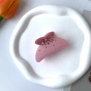 Vue détaillée d'une pince à cheveux rose avec strass sur un plateau en céramique blanche