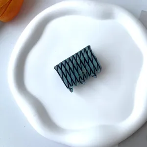 Detail of teal acetate hair clip with black grid pattern and gold France Handmade text