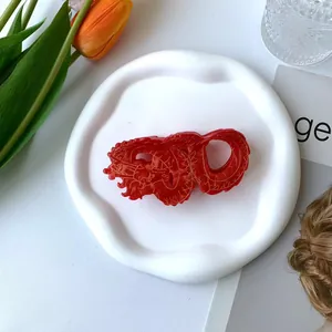 Elegant red Chinese dragon hair claw clip with gold textures on a white textured tray