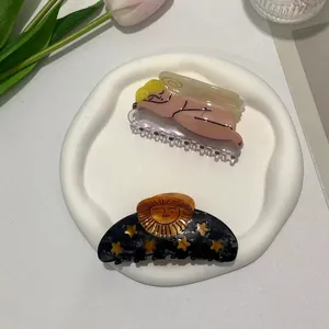 Detail view of cute cupid and moon celestial pattern hair clips on a white ceramic tray