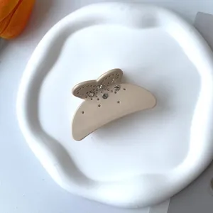 Gros plan sur une pince à cheveux mate beige ornée de strass sur un plateau blanc