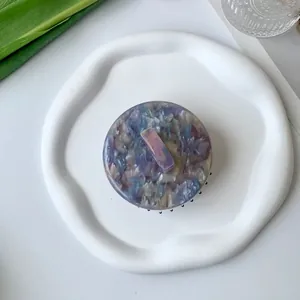 Top view of a marbled acetate hair claw clip with dark blue and purple patterns on a white tray