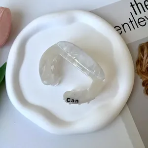 Close-up of white marble acetate hair claw clip with Can engraving on a ceramic tray