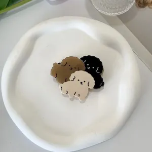 Dettaglio di tre mollette per capelli cuccioli in acetato marrone, nero e crema su vassoio