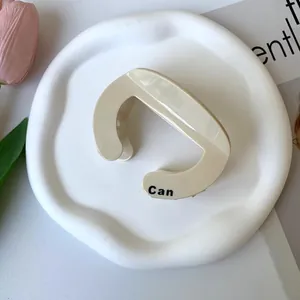 Detail of cream marble acetate hair claw clip with black lettering on a wavy plate