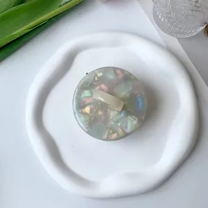 Detailed top view of a round pearlescent acetate hair claw on a white ceramic plate