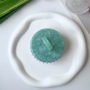 Top view of a marble-textured scalp massage brush with green handle and black bristles