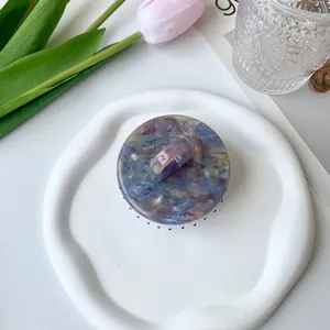 Artistic round acetate hair claw clip with purple and gold marble pattern texture