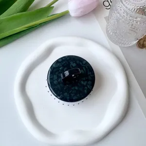 Close-up of a tortoiseshell acetate scalp massage brush on an artistic white tray