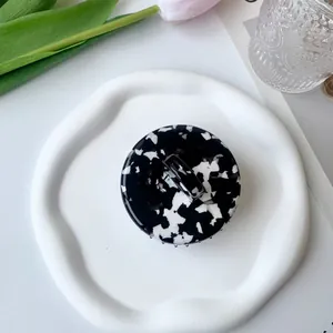 Close-up of marble pattern acetate scalp massage brush on an elegant ceramic plate