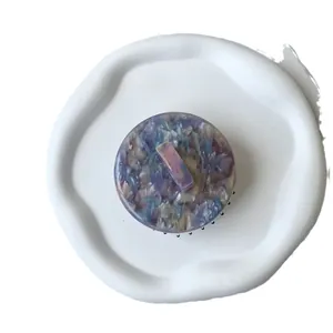 Round marble acetate massage comb with purple and blue patterns on a white decorative plate