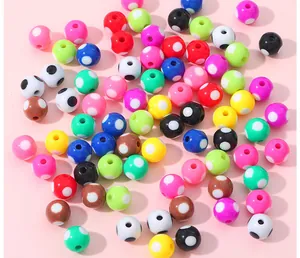 Nahaufnahme bunter Acrylperlen mit Punkten für DIY-Schmuck auf rosa Hintergrund