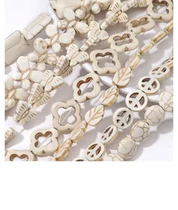 Macro shot of white synthetic turquoise beads in butterfly, flower and leaf shapes