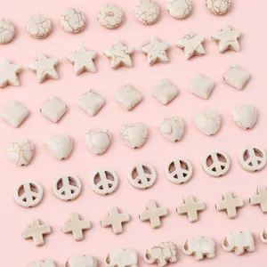 Various shapes of white turquoise stone beads for DIY jewelry making on pink background
