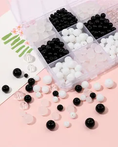 Gros plan de perles en verre de cristal DIY noir, blanc et clair dans un plateau en céramique