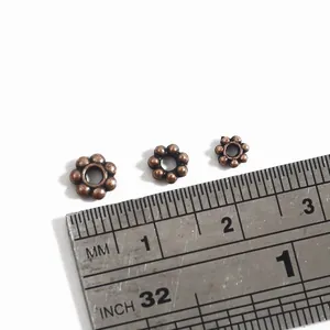 Retro bronze plum blossom spacers for handmade DIY jewelry, displayed with scale ruler