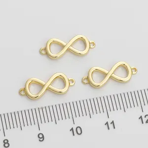 Three gold infinity charms with loops for DIY jewelry making on a white textured background