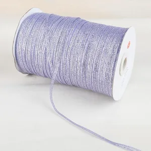 Detail of lavender glitter ribbon with metallic thread wound on white spool