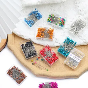 Makroaufnahme von farbigen Perlkopfstecknadeln in Aufbewahrungsboxen für DIY-Schmuck