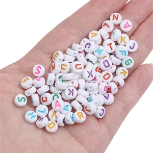 White acrylic flat round beads with colorful letters held in palm for size scale