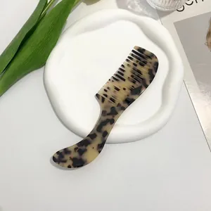 Detail of ergonomic tortoise shell acetate hair comb with leopard print on ceramic tray