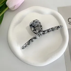 Close-up of black and white marble pattern acetate hair claw clip on a white tray