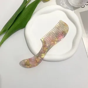 Detailed view of pink marble acetate wide-tooth comb on a decorative ceramic tray