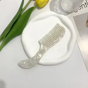Detailed view of wide-tooth acetate hair comb with marble pattern in a lifestyle setting